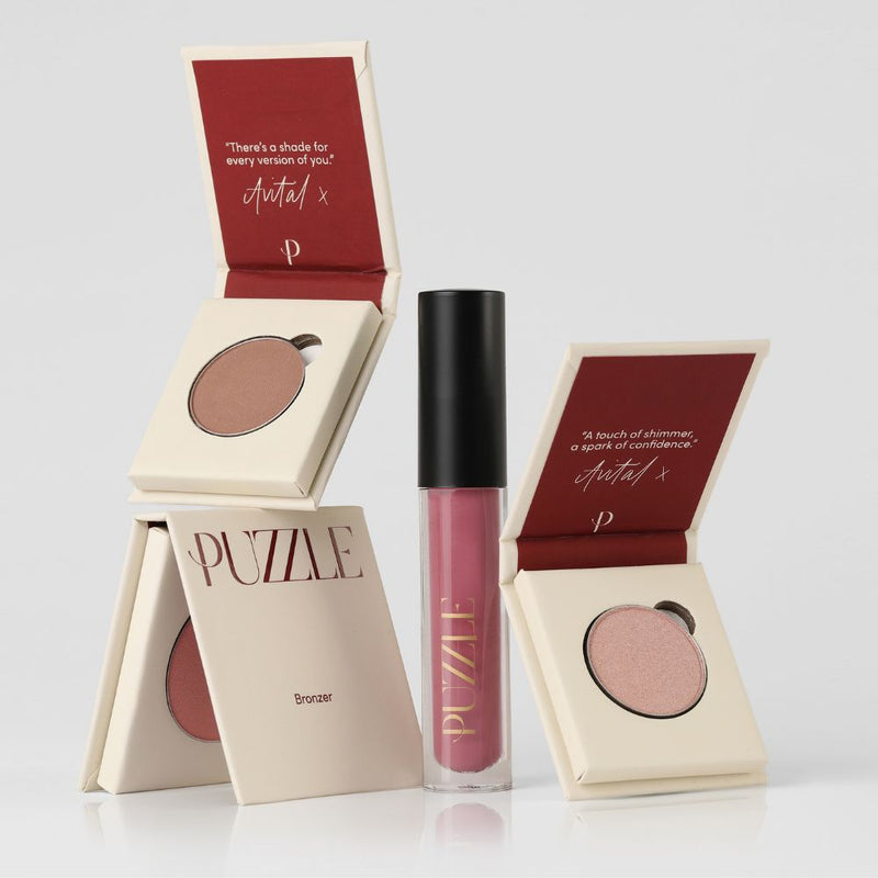 Makeup products including a lip gloss and blushes with 'PUZZLE' branding on a light gray background.