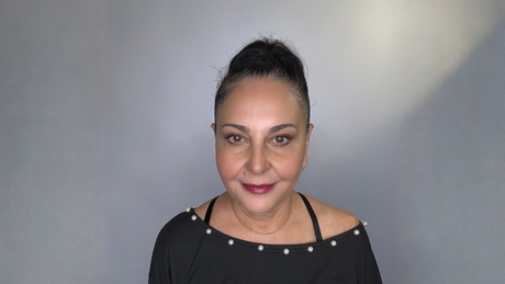 Woman with mature skin and natural makeup look against a neutral background, demonstrating real skin texture and a healthy, radiant finish